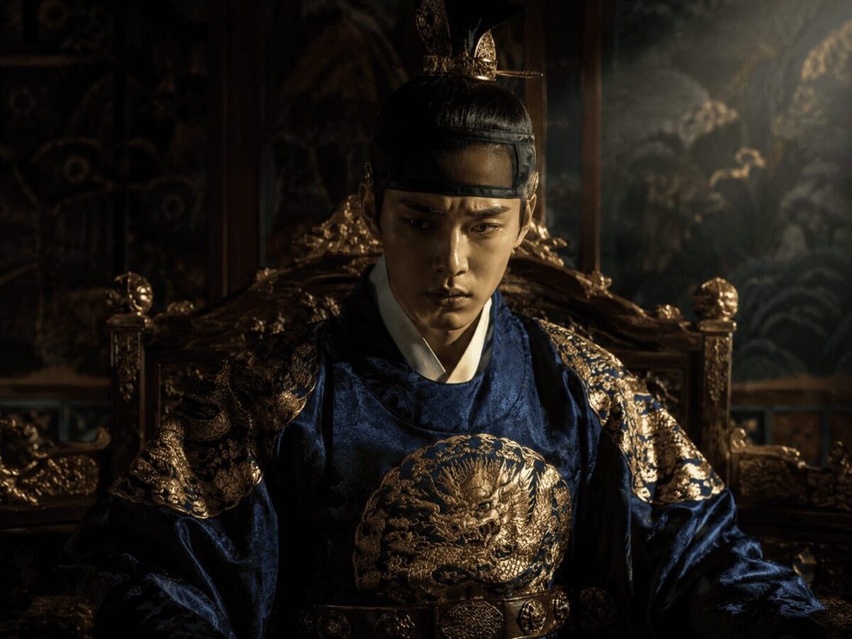 A young Joseon king in royal blue and gold robes seated on the throne, representing Yeonsan-gun