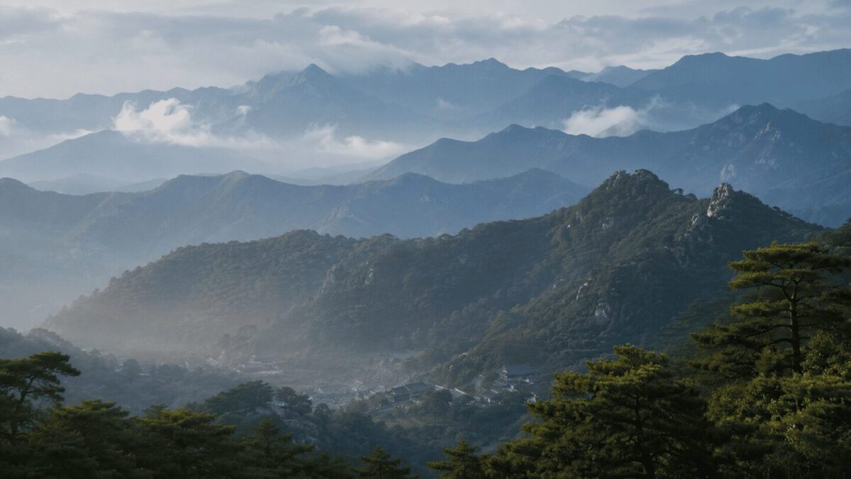Layered Korean mountains rising behind a small village, the landscape that gave rise to mountain spirit worship