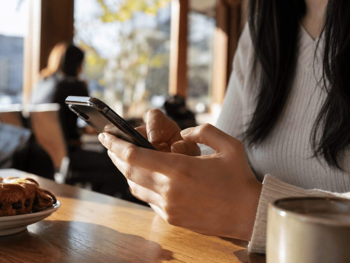 A person typing on a smartphone in a warm Korean café
