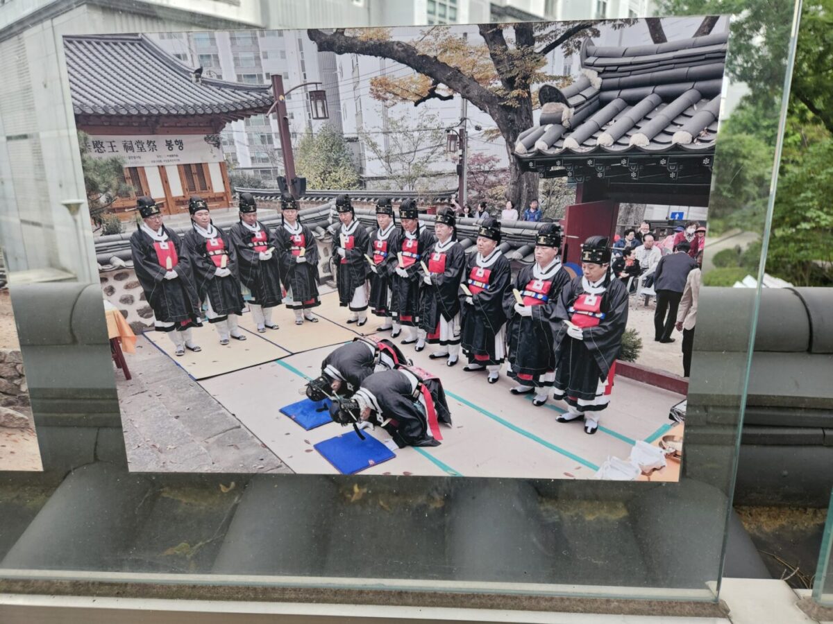 A row of officiants in black and red ceremonial robes standing in formation during the Gongmin shrine memorial rite in Seoul